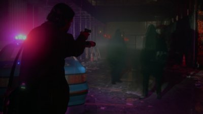 Captura de pantalla de Alan Wake 2 que muestra a Alan empuñando una pistola y alumbrando a varias figuras sombrías