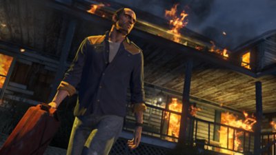 لقطة شاشة لـ Grand Theft Auto V تظهر فيها إحدى الشخصيات الرئيسية، Trevor، وهو يخرج من مبنى محترق بينما يحمل في يده عبوة وقود