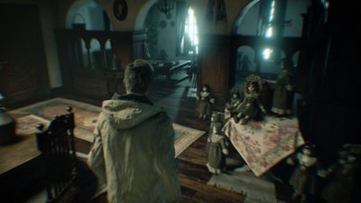 Resident Evil Village – posnetek zaslona s prikazom tretjeosebnega pogleda na Ethana Wintersa v sobi, polni lutk