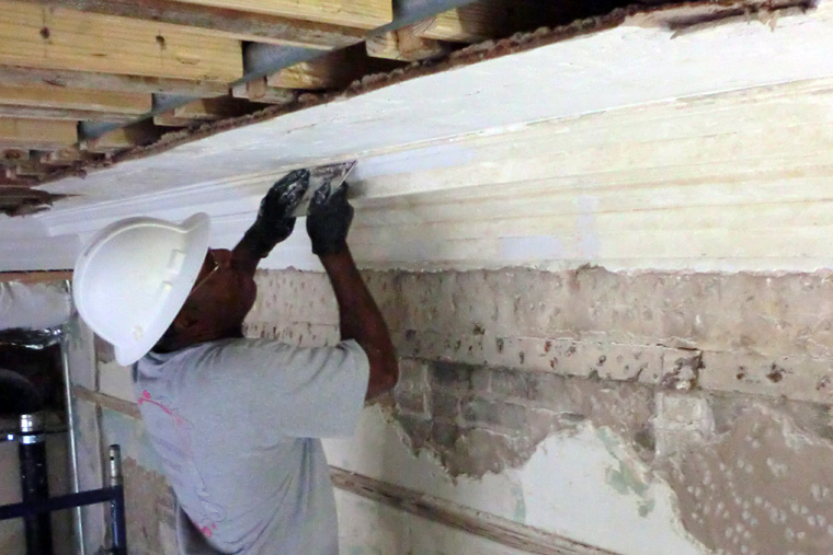 A Worker is Cleaning and Replastering an Interior Mansion Wall