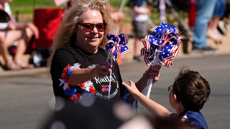 A woman hands out patriotic pinwheels during the Colorado 4th at Firestone parade to mark the...