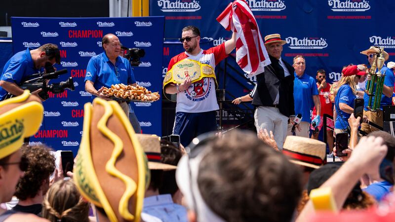 Patrick Bertoletti, center, reacts after winning the men's division in Nathan's Famous Fourth...