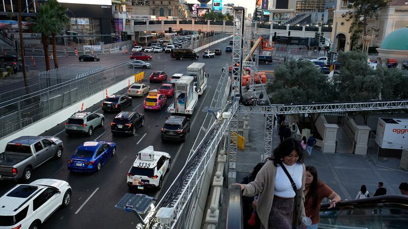 Pedestrians take an escalator along the Las Vegas Strip beside rigging and fencing installed...