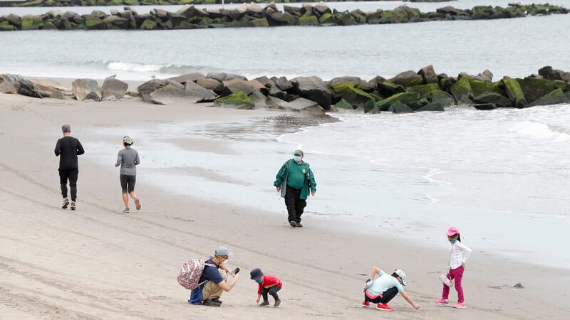 FILE- Children play in the sand while others jog as a New York City Parks officer, center,...