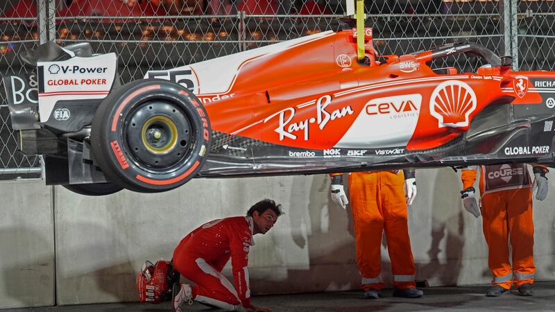 Ferrari driver Carlos Sainz, of Spain, looks at the bottom of his car after running over a...