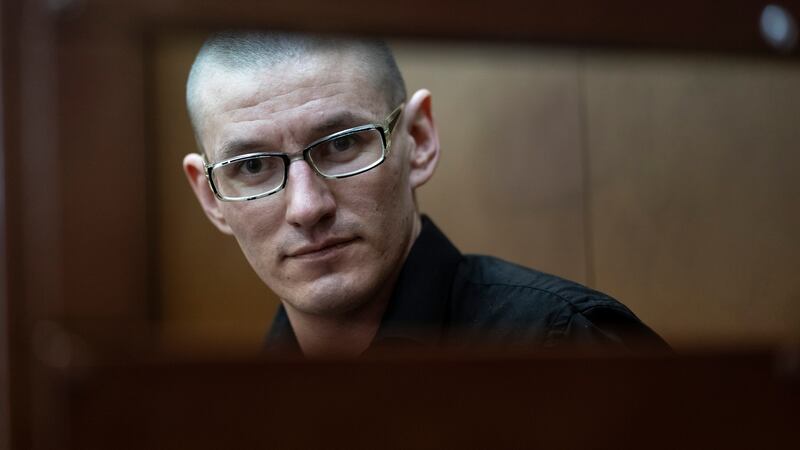 FILE - U.S. citizen Robert Woodland Romanov sits in a defendant's cage before a court session...