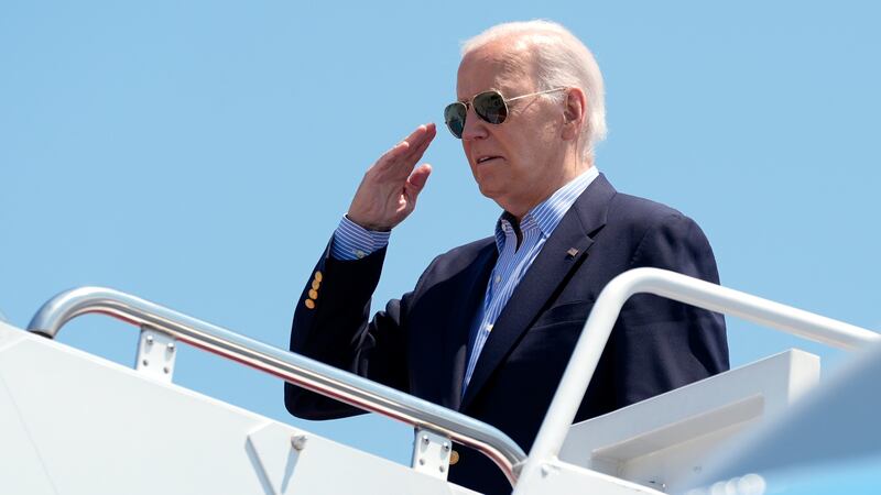 President Joe Biden salutes as he boards Air Force One at Andrews Air Force Base, Md., en...