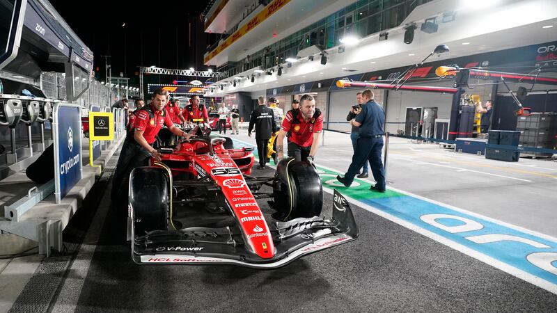 The crew for Ferrari driver Carlos Sainz, of Spain, pushes the car down pit lane before the...