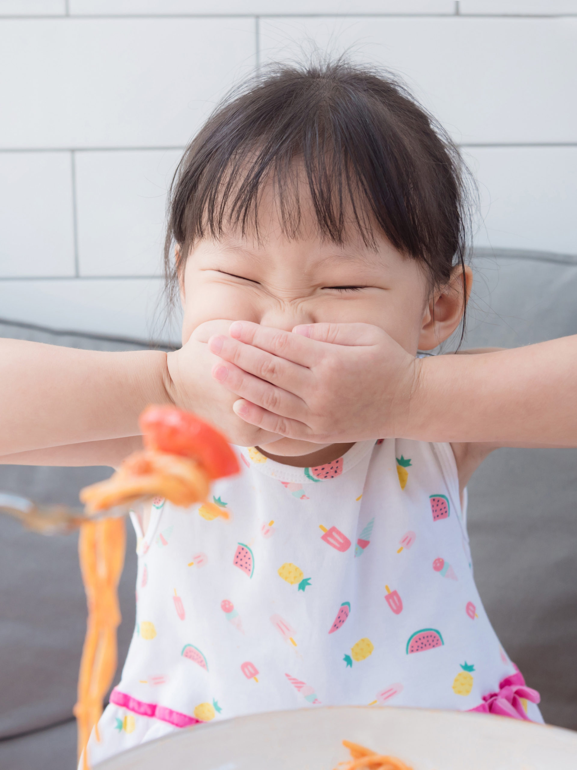 girl covers her mouth with hands refusing to eat tomato amd spaghetti