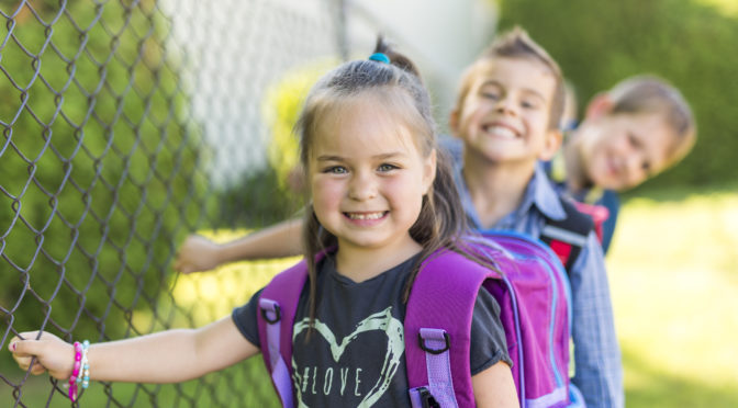 little girl on the first day of school with her classmates waiting in line