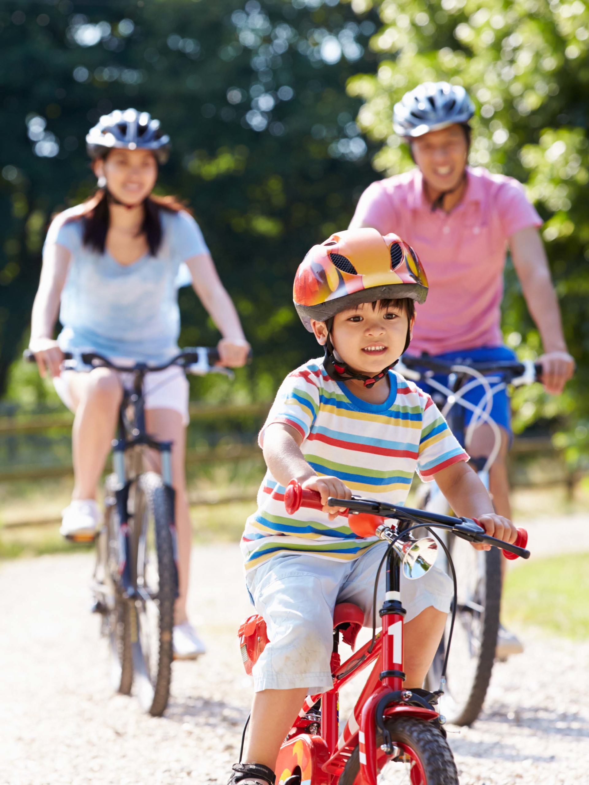 family bike riding in park together and smiling