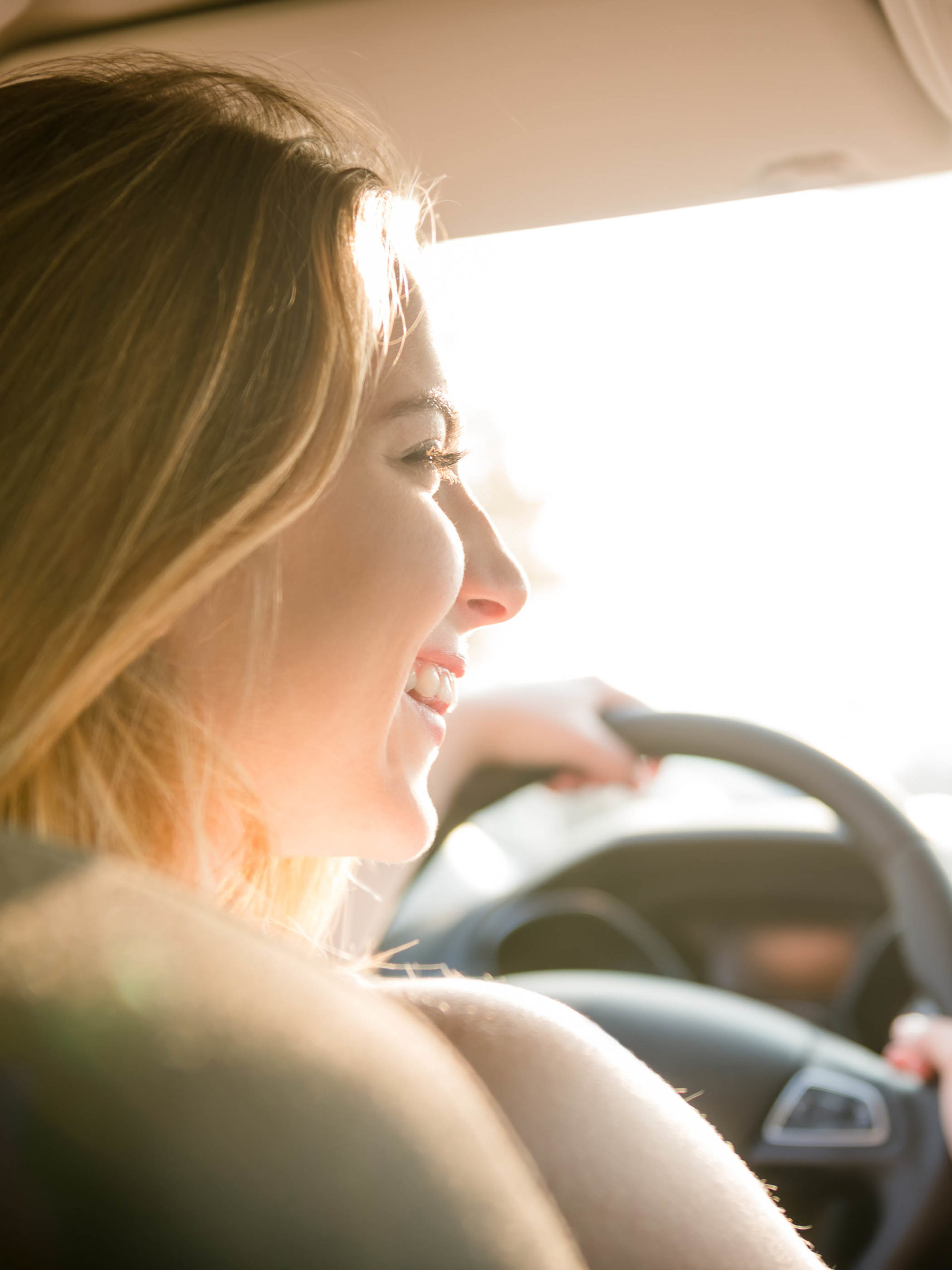 Teenage girl driving car sun shining through windshield