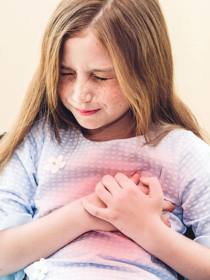 little girl clutching her chest in pain and grimacing