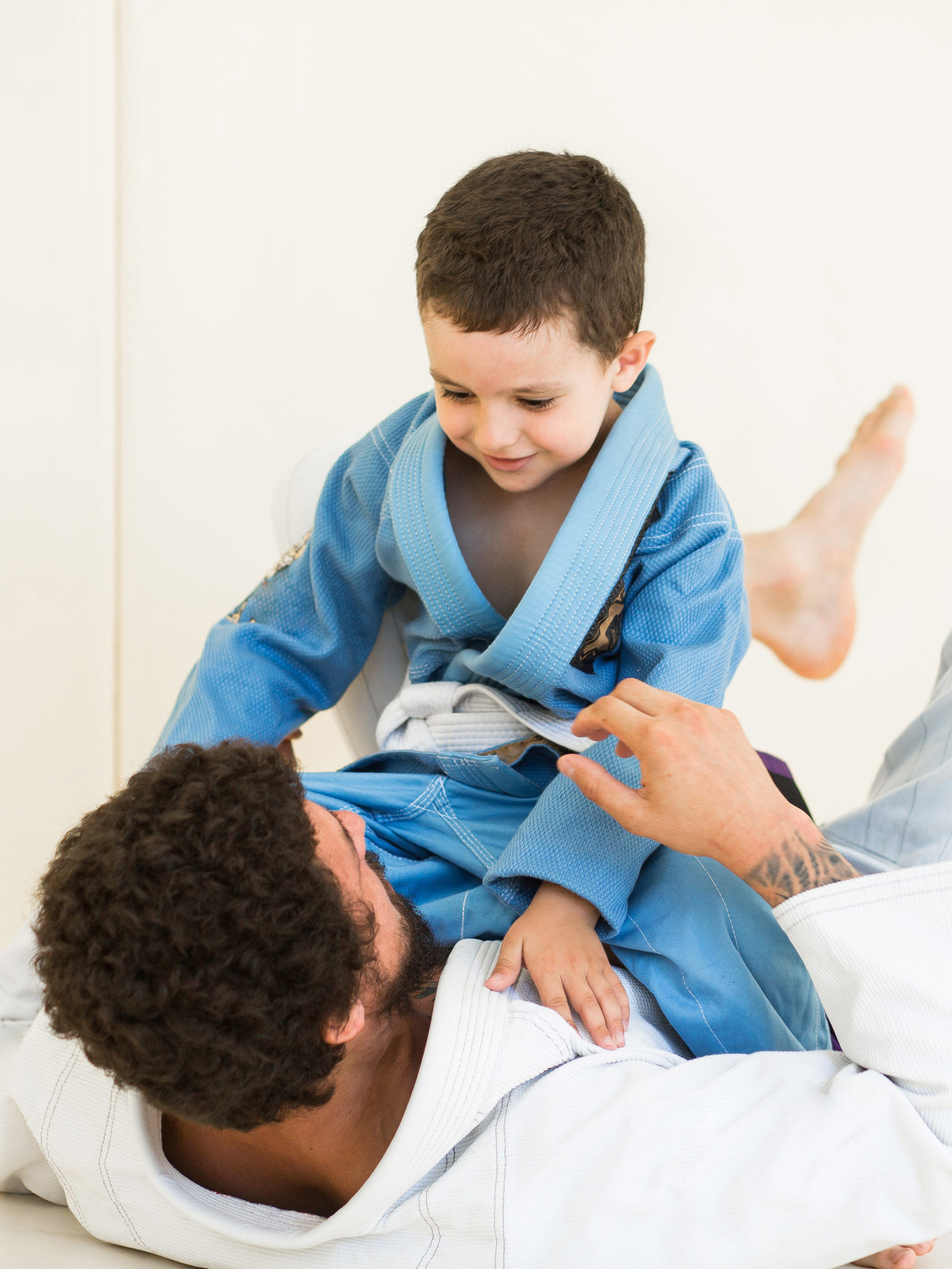 Father and little kid son are engaged in wrestling jiu-jitsu in the gym