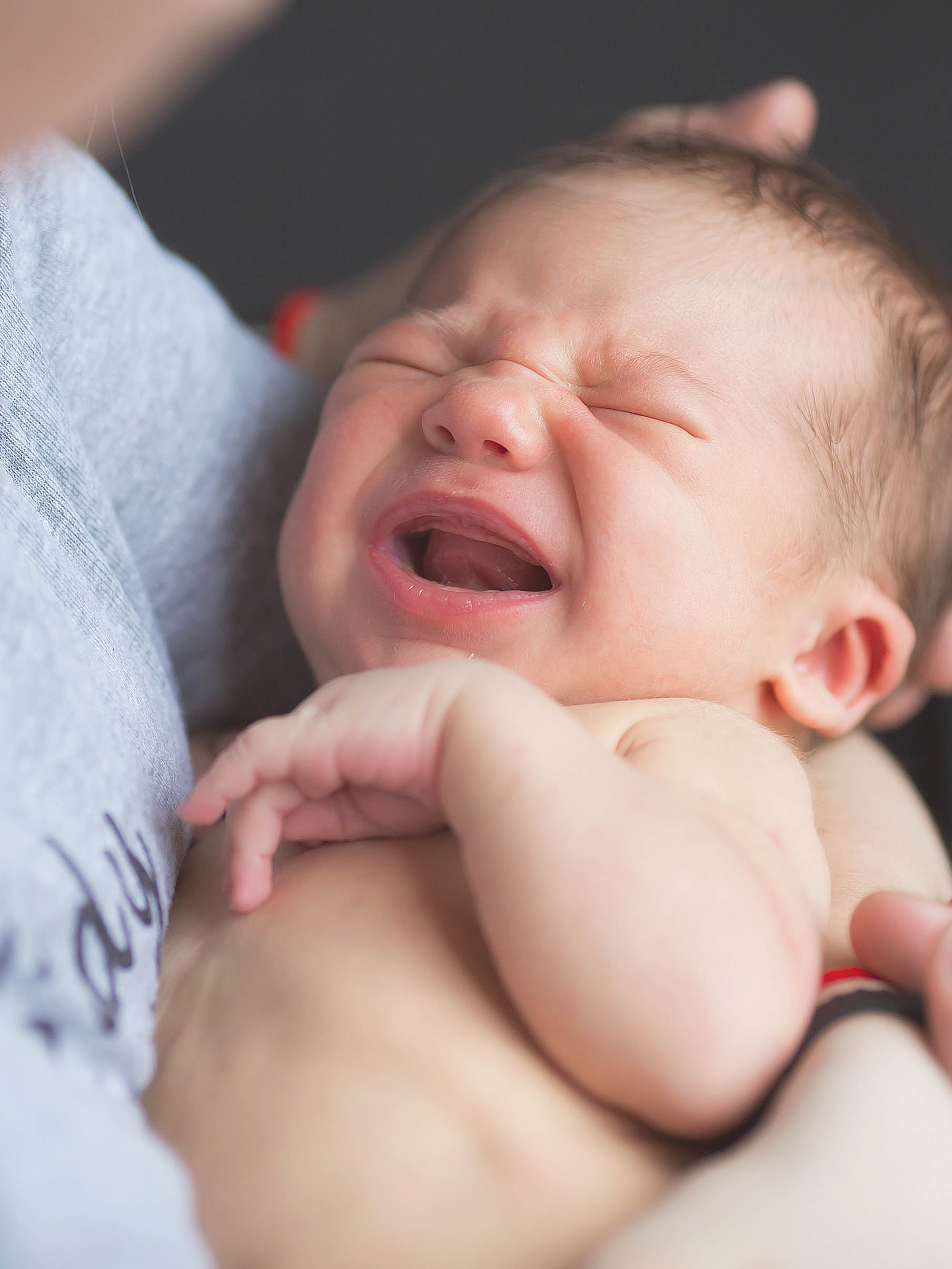 parent trying to calm crying baby in his arms