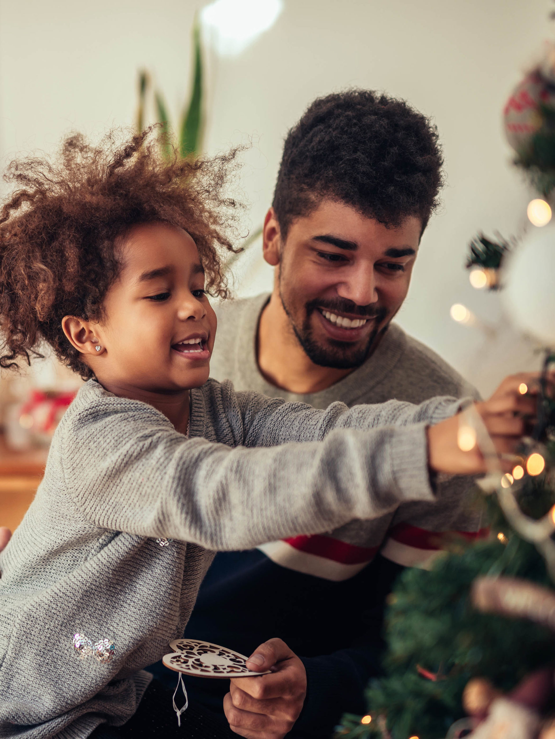 girl decorating Christmas tree with dad