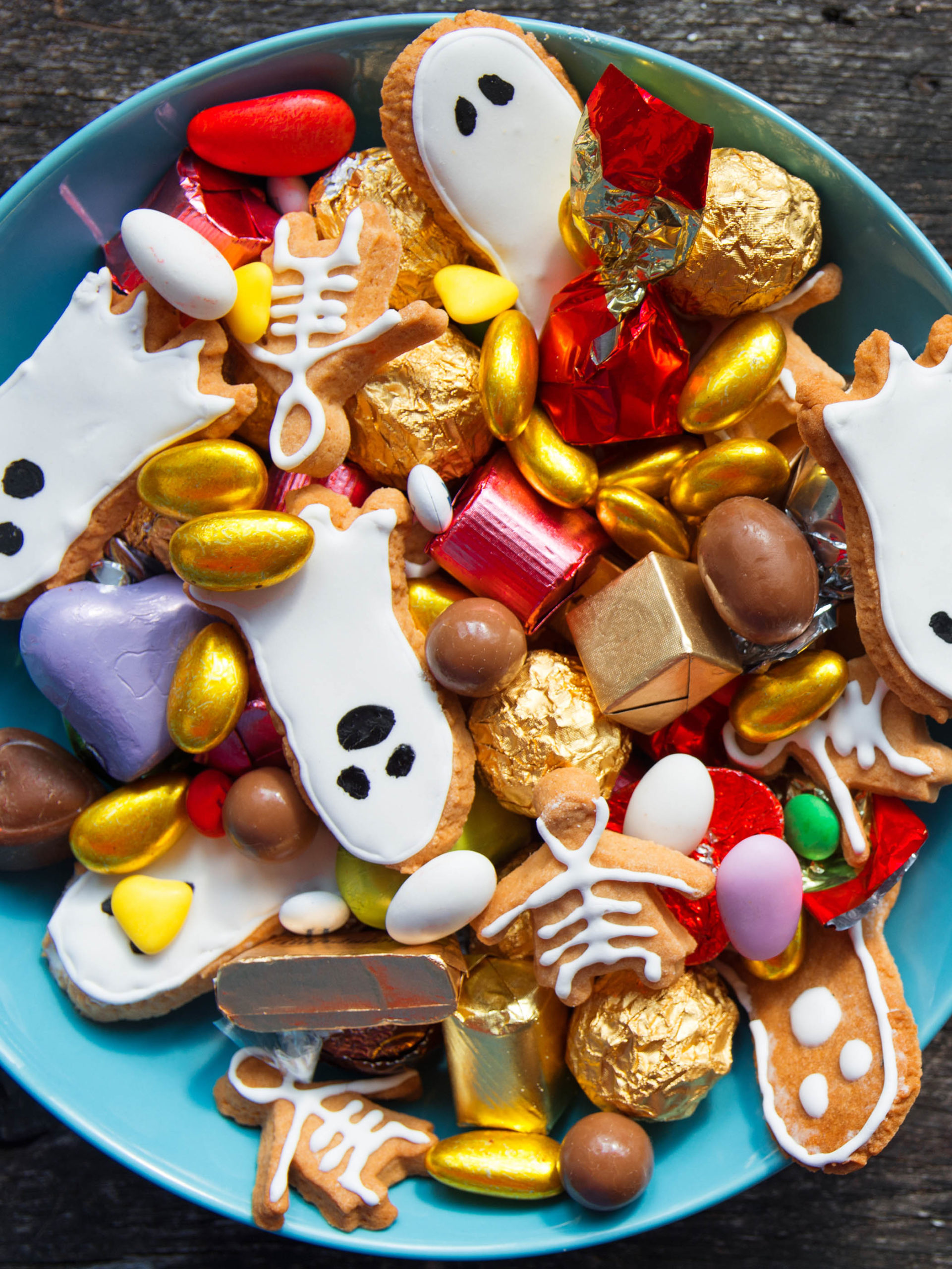 bowl filled with Halloween candy and cookies shaped like ghosts