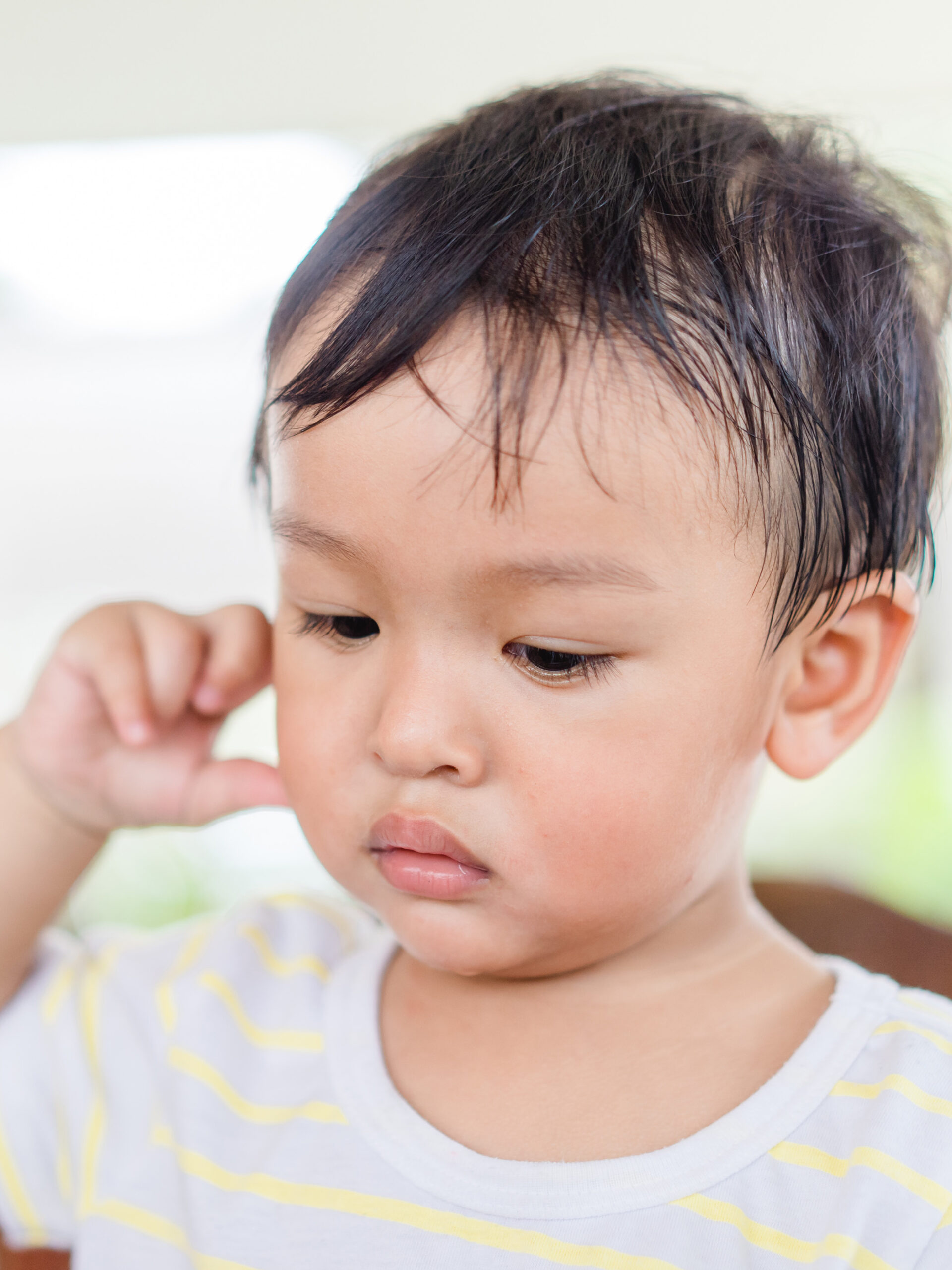 Little boy puts finger in ear