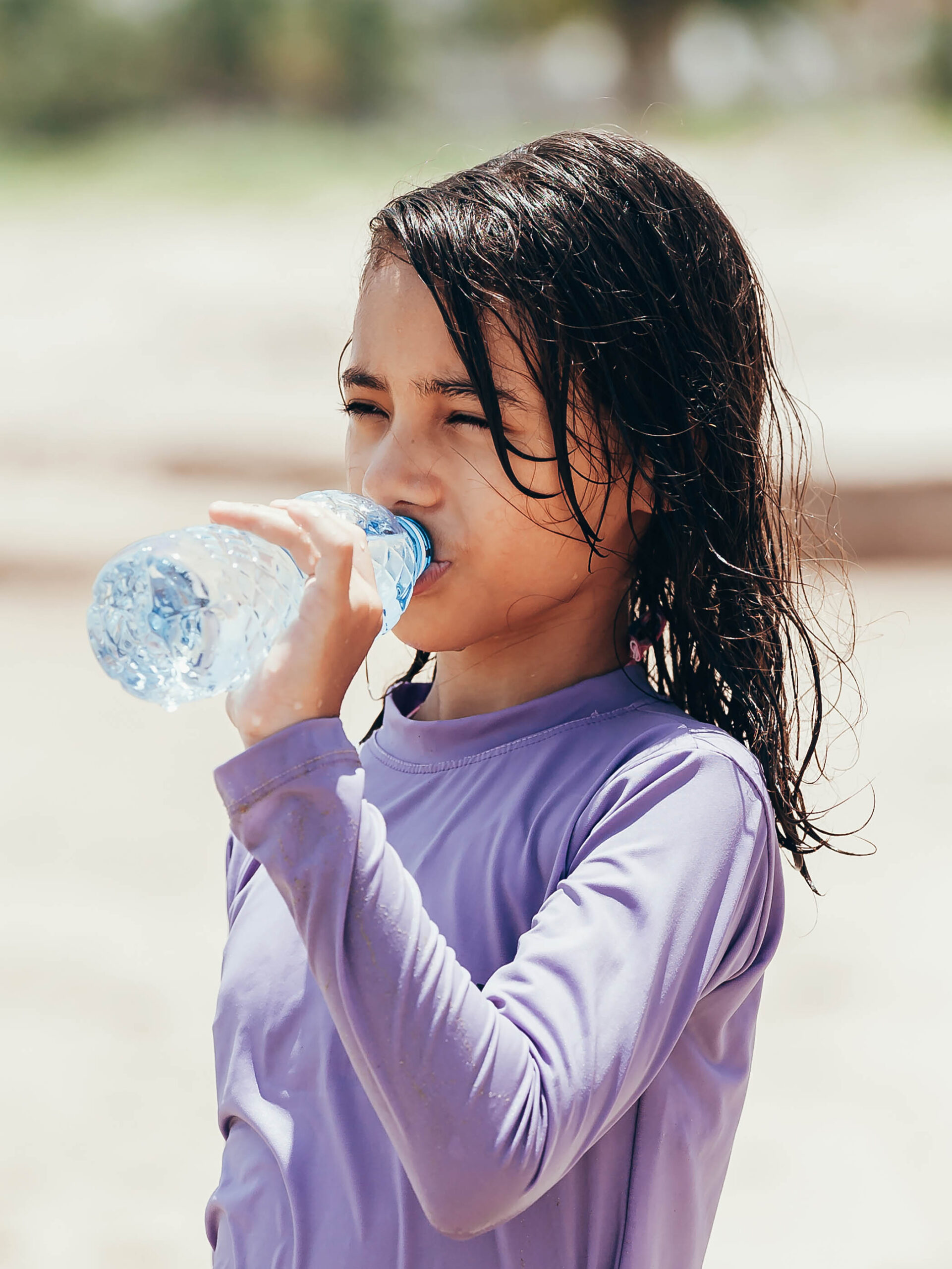 little girl drinking water on the beach