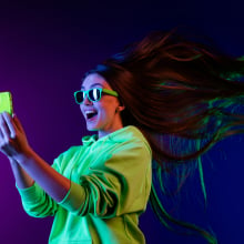 Woman wearing green hoodie and holding green phone