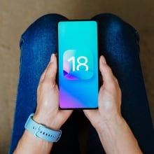 A person holding a phone with iOS 18