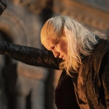 Daemon Targaryen braces himself against a wall with one hand, staring deep into a fireplace.