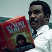 A man in a white button-up and dark tie reads a book titled "The You You Are"