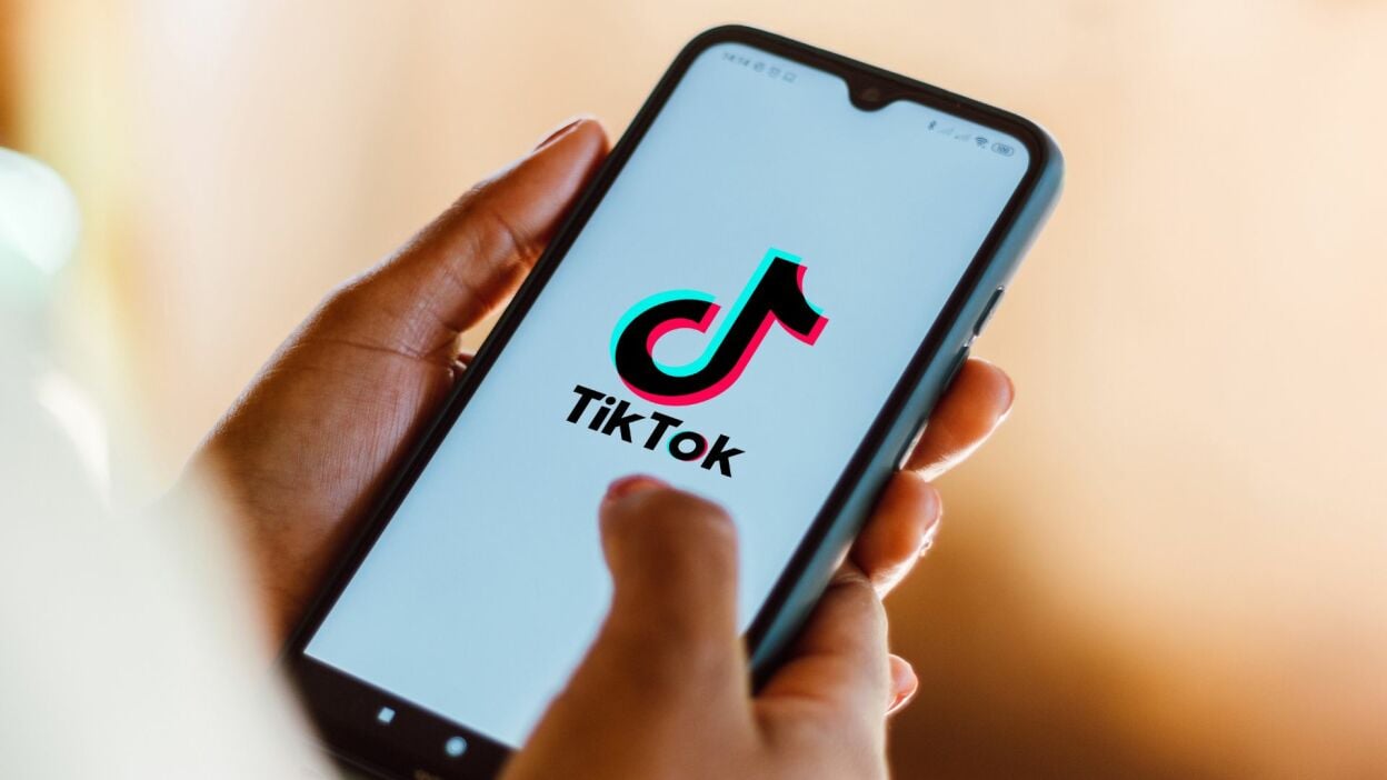 A person holding a phone with the TikTok logo.