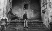 A man stands on an Italian public staircase, looking over his shoulder.