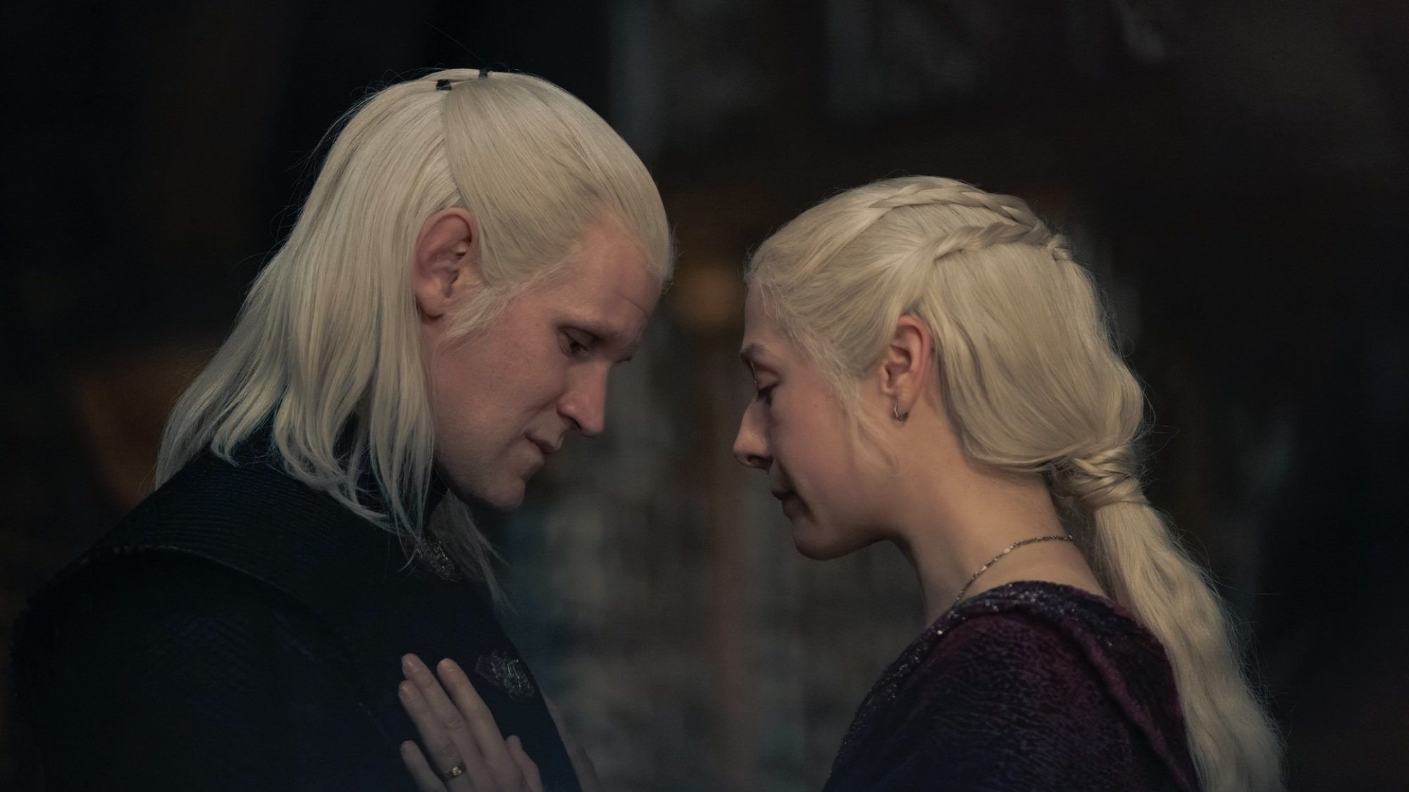 Rhaenyra and Daemon Targaryen standing face to face; Rhaenyra puts her hand on Daemon's chest.