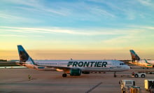 Frontier plane on ground at airport with sunset in background