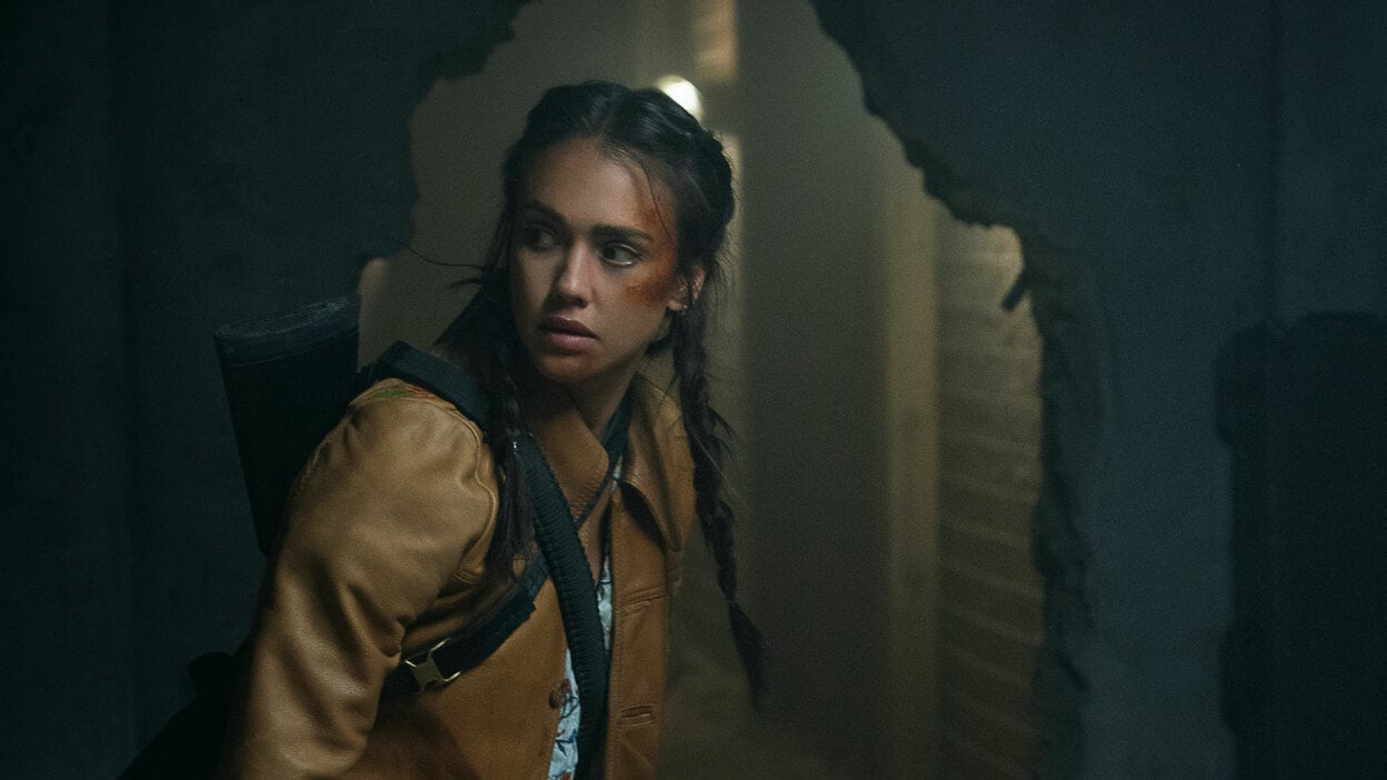 A woman with a bruised face creeps through a dark, abandoned building.