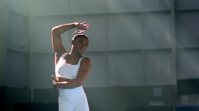 Simone Biles in a dance pose in a studio.