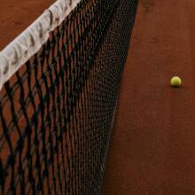 Tennis net and ball on a clay court