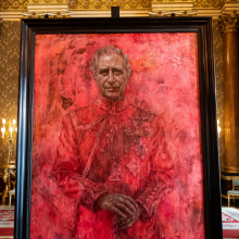 A portrait of King Charles in a black frame. The portrait is mostly red, and a butterfly is about to rest on the King's shoulder.