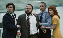 Four colleagues, three men and one woman, stand huddled together in an office in an episode of "Severance."