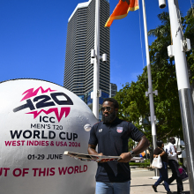 USA Cricket Vice-Captain Aaron Jones taps a ball with a bat next to a giant T20 marketing cricket ball