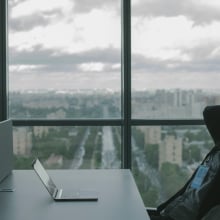 Person sitting with hands behind head leaning back and looking at laptop on desk