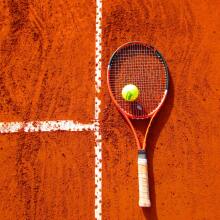 Tennis racket and ball on clay court