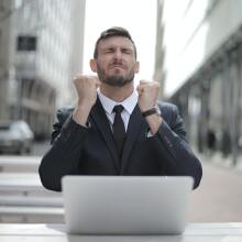 Man grimaces in fron of laptop