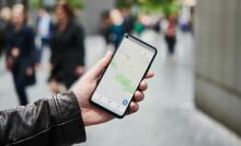 Detail of a man holding up a smartphone with the Google Maps app visible on screen.