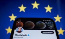 Elon Musk's bluecheck account on a phone against a European Union flag. 