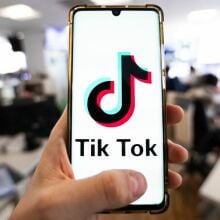 A man holding a smartphone displaying the logo of TikTok.