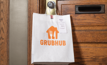 a white paper bag with a grubhub logo hangs on the doorknob of a front door