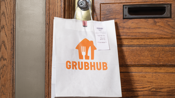 a white paper bag with a grubhub logo hangs on the doorknob of a front door