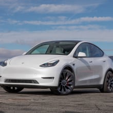 A white Tesla Model Y with a mountainous background.