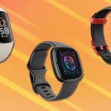 three fitbit fitness trackers sit on an orange background with white streaks