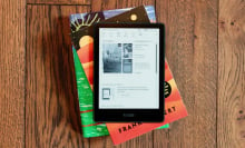 kindle paperwhite signature edition on stack of books on wood floor