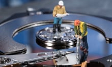 miniature worker figurines on hard drive