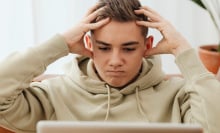 Person holding their head in frustration while looking at computer